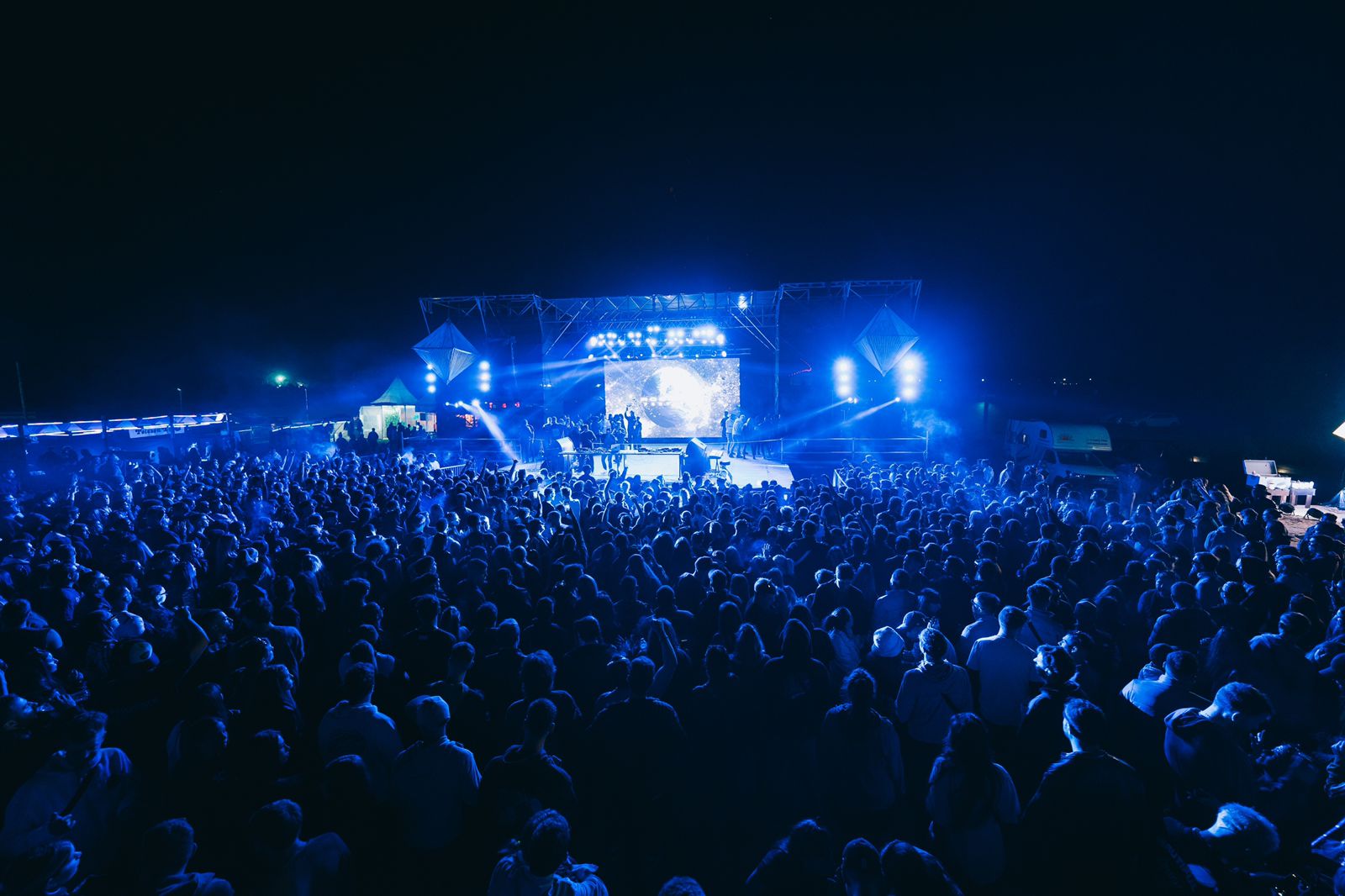 Multitud iluminada en azul frente al escenario · registro real Roswell